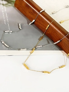 Detail of minimalist 18K gold and silver cube beads on a fine titanium steel necklace