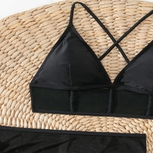 Sexy schwarzer vierteiliger Bikini mit Netz-Einsatz auf Webmatte für den Strandurlaub