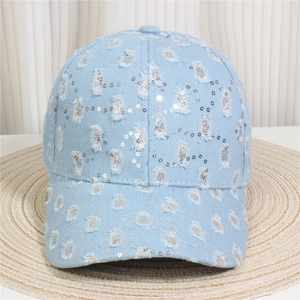 Close-up of light blue denim baseball cap with distressed holes and silver sequins