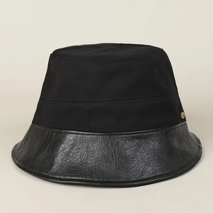 Close-up of black cotton fisherman hat featuring a sleek faux leather brim and metal logo
