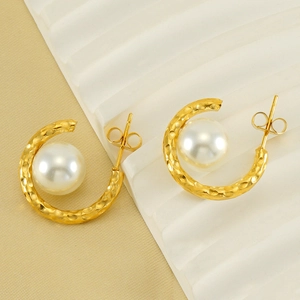 Détail de boucles d'oreilles dorées martelées en C avec perles blanches et fermoirs