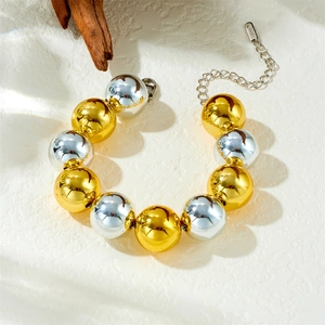 Collier chaîne à billes bicolores or et argent en acier inoxydable sur une surface en bois