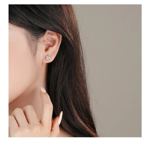 Macro shot of a silver sunflower ear cuff featuring zircon stones on a model's ear