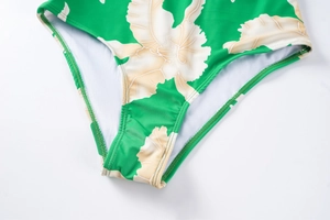 Detail of green floral swimsuit with ruffles and high-cut leg showing fabric texture