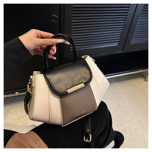 Detail of a contrast color leather handbag with golden hardware and fashion lettering