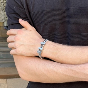 Close-up of men's silver Cuban link bracelet with rectangular plate on wrist