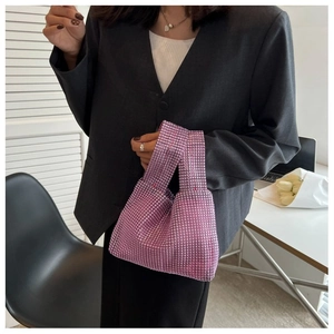 Gros plan du sac à main rose en strass sur blazer gris montrant les détails brillants