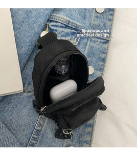 Detailed internal compartments of the black canvas mini bag holding earbuds and small spray bottle