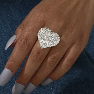 Close-up of a glamorous silver heart ring pavé-set with sparkling crystals on denim background
