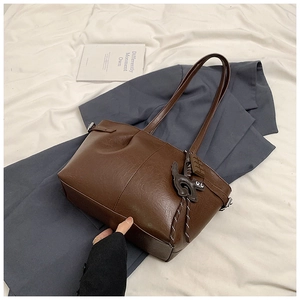 Detail view of brown vintage pleated tote bag with creative chocolate and cartoon pendants