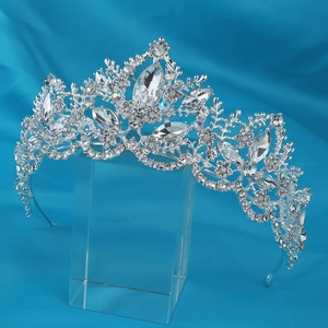 Detailed view of silver bridal crown with intricate crystal floral motifs on blue satin