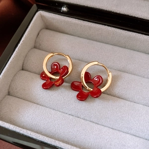 Vue macro de boucles d'oreilles fleurs rouges et anneaux dorés sur écrin en velours gris