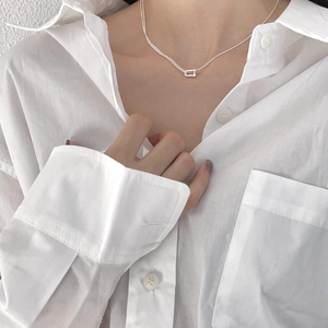 Macro detail of silver U-shape link pendant on a minimalist sterling silver necklace