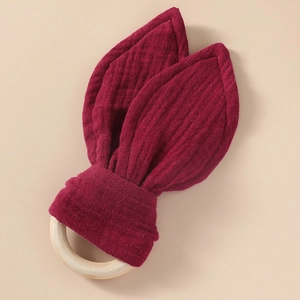 Detail view of cotton muslin rabbit ear teether toy with natural wooden ring for infants