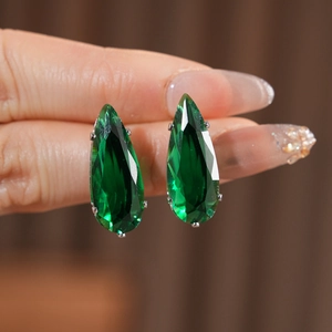 Close-up of teardrop emerald green cubic zirconia earrings with silver claw setting