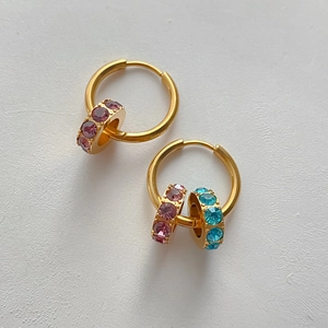 Nahaufnahme von goldenen Edelstahl-Creolen mit bunten, Zirkonia-besetzten Anhängern.