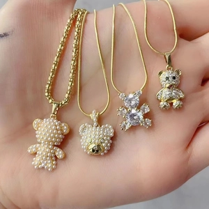 Macro shot of 4 gold bear necklaces featuring pearls and rhinestones on chains