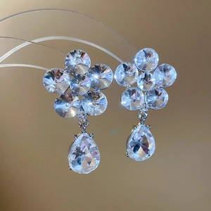 Macro detail of silver drop earrings with floral crystal studs and waterdrop pendants