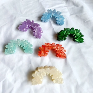 Selection of vibrant wavy flower hair claws in purple, green, and blue acrylic finish