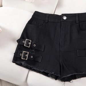Close-up of black high waist denim shorts featuring silver side buckles and frayed hems