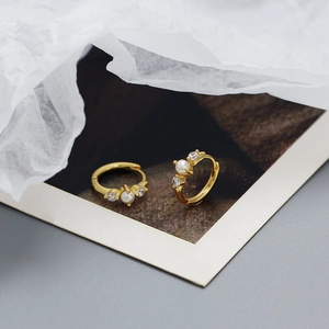 Close-up of gold hoop earrings with natural pearls and sparkling zircon stones