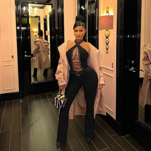 Sexy schwarzer Jumpsuit mit Ösenschnürung und beigefarbenem Trenchcoat in Luxusambiente