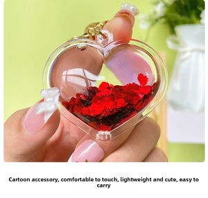 Close-up of heart-shaped transparent keychain with red heart sequins and gold ring