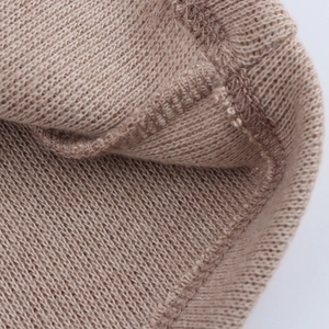 Macro view of light brown knit fabric with detailed double stitching and soft texture
