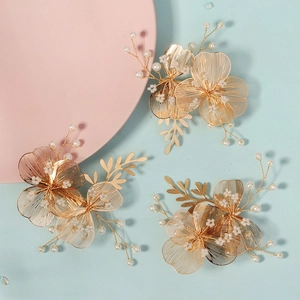 Detail view of 3 gold wire floral hairpins with white pearls for bridal occasions
