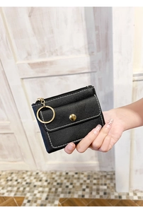 Detail of black lychee leather coin purse with gold hardware and white stitching
