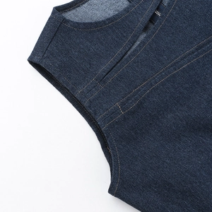 Detailed macro shot of dark blue denim fabric with orange contrast stitching on vest