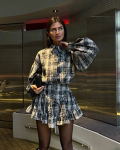 Street style shot of a grey plaid shirt and ruffled mini skirt two-piece set on a model
