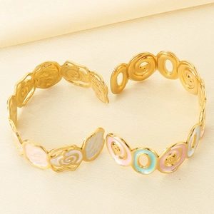 Detailed macro view of gold-tone spiral bracelets with colorful floral enamel patterns