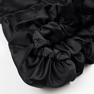 Gros plan sur la texture en soie mesh noire avec détails plissés sur une robe courte