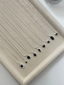 Detailed display of silver necklaces with black agate pendants on a grey velvet jewelry tray