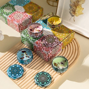 Macro view of four colorful mandala pattern tin candles with dried flowers on a wooden tray