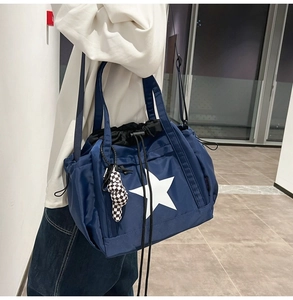 Detail of blue nylon tote bag with star print and checkered bear charm accessory