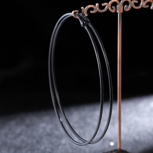 Close-up of minimalist black oversized hoop earrings on a vintage bronze jewelry stand