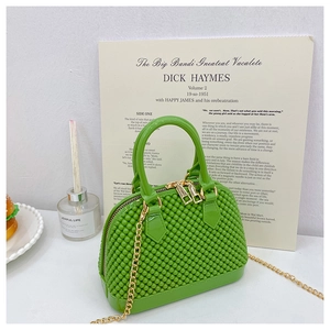 Detail of lime green woven PVC jelly handbag with golden chain and hardware accents