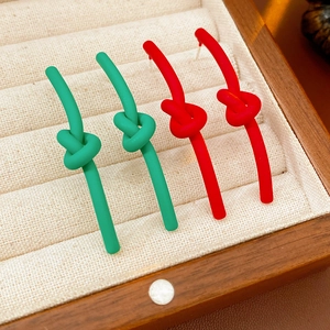 Close-up of matte red and green knotted stud earrings in a beige jewelry display box