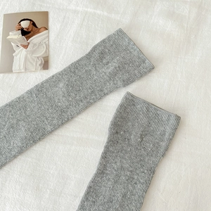 Detailansicht grauer Rippstrick-Beinstulpen mit weicher Textur auf weißem Stoffhintergrund