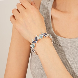 Detail view of a model wearing the gradient blue butterfly enamel stretch bracelet