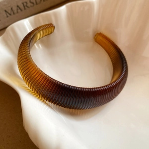 Detailed view of an amber resin open cuff bracelet with a refined ribbed texture finish
