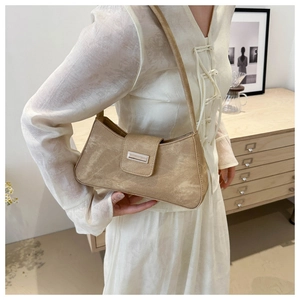 Close-up of khaki suede crescent bag featuring a decorative metal buckle detail