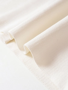 Close-up of ivory white ribbed knit fabric showing fine texture and clean edge piping
