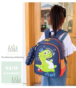 Detail view of navy blue kids backpack with green cartoon dinosaur and orange zippers