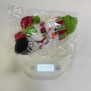 Detail showing plush snowman wine bottle cover weight at 39.9g on digital scale