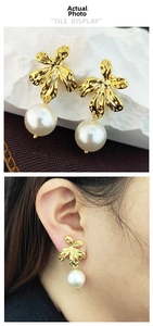 Detail of leaf-shaped gold earrings with large white pearls shown on a model