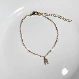Detail of 18K gold plated bracelet with sparkling zircon letter R pendant and adjustable chain