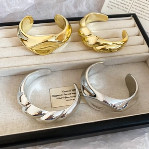 Detailed view of gold and silver twisted and smooth acrylic metal bangles on velvet tray